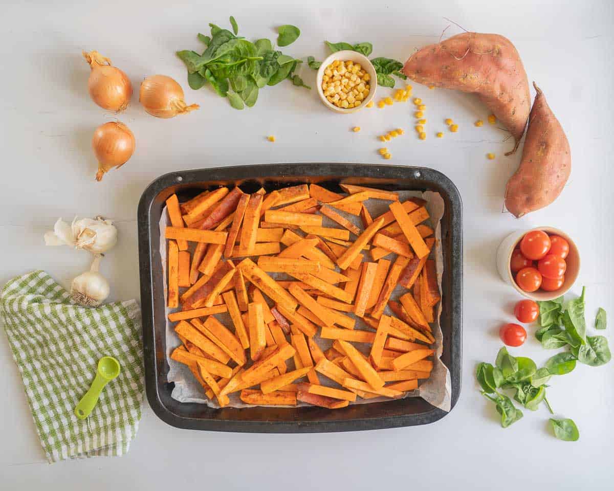 Kumara chips oiled and spiced in a roasting tine ready to go into the oven.