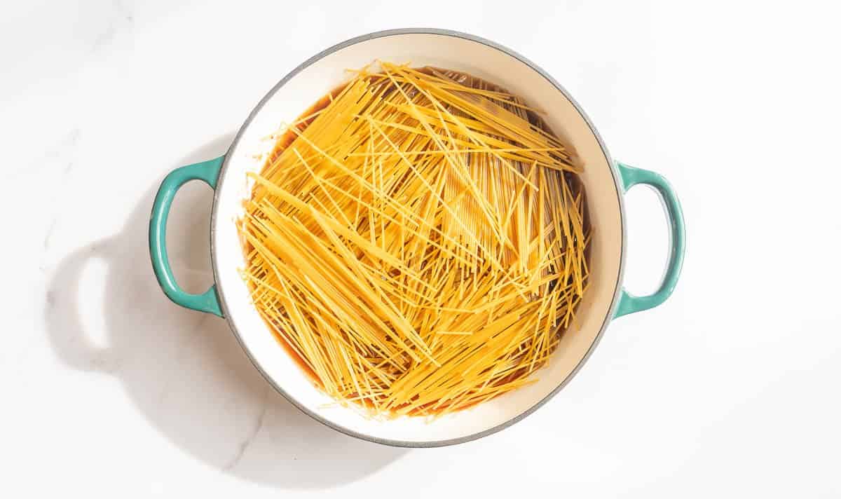 Dry spaghetti sprands lying in the bottom of a casserole dish.