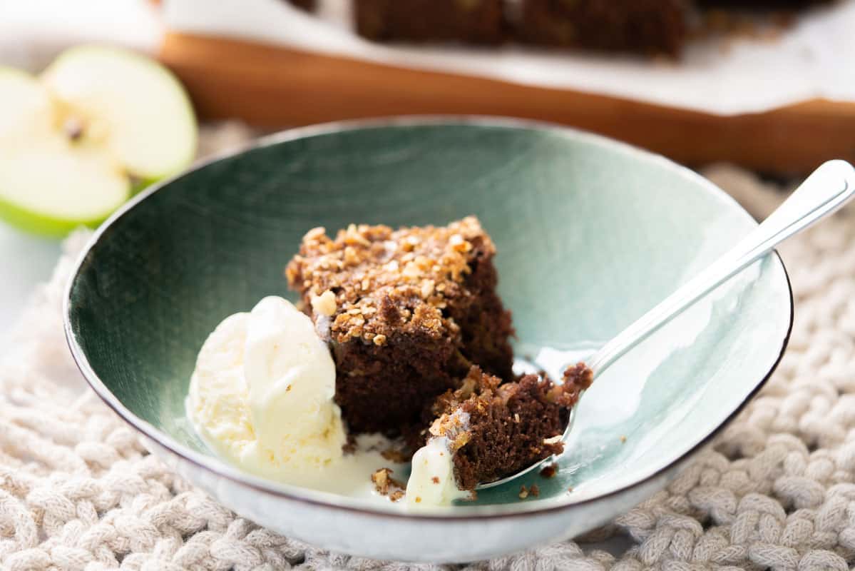 A piece of chocolate cake served in a green bowl with ice cream.