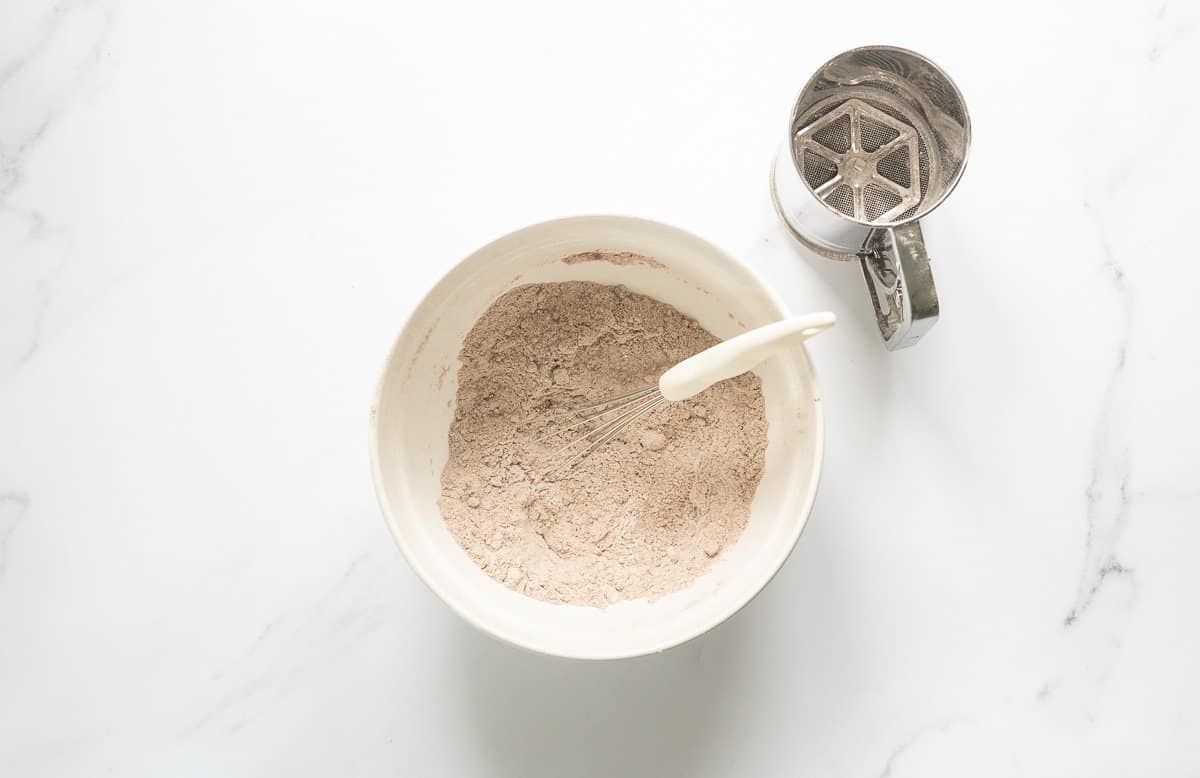 Sifted dry ingredients is a large white ceramic bowl.