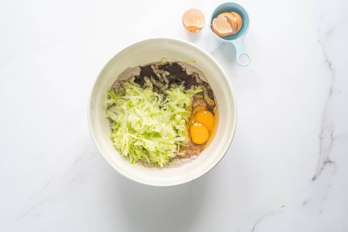 Grated apple and eggs added to cake batter dry ingredients.