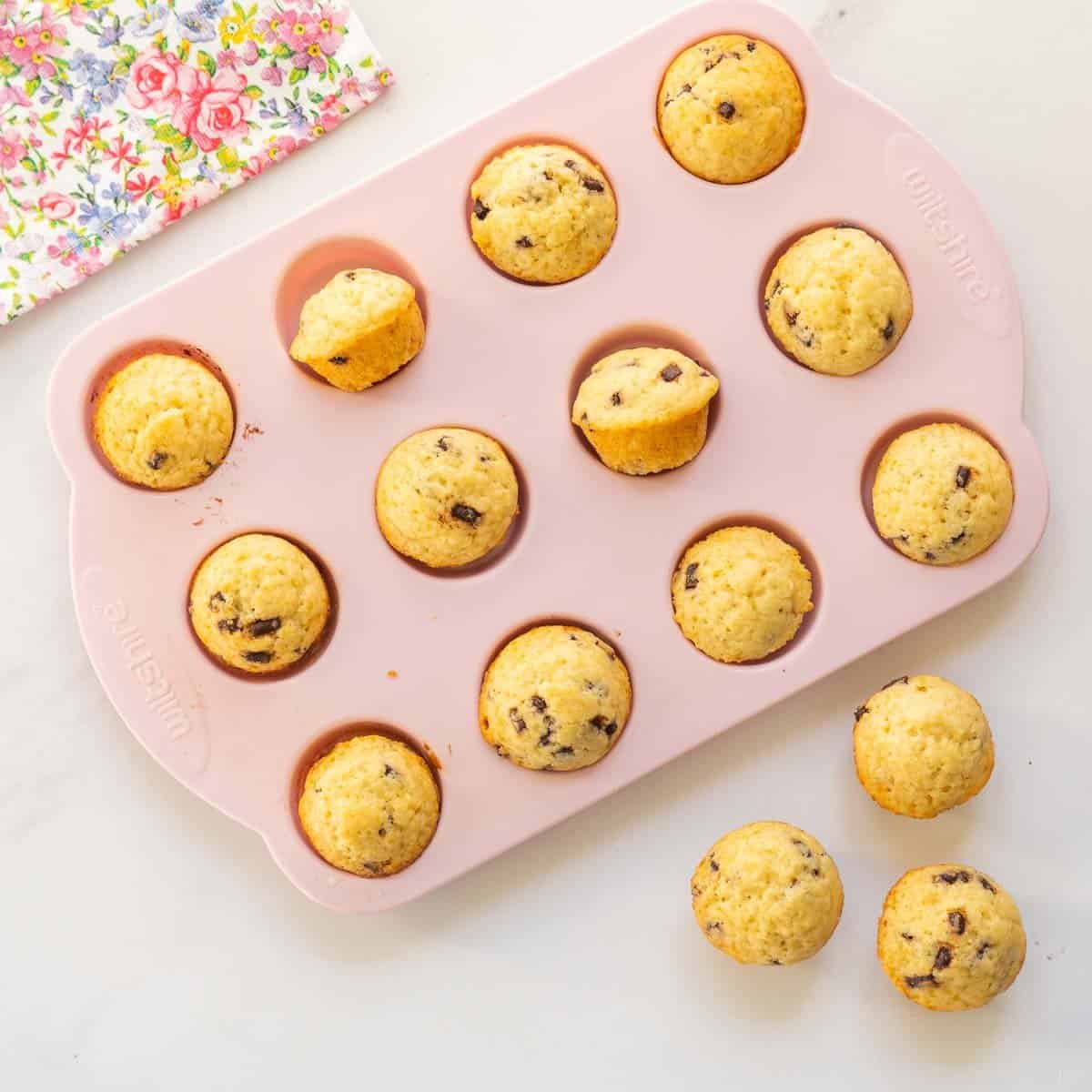 Mini muffins in a pink silicone muffin tray ready to come out of the tray.