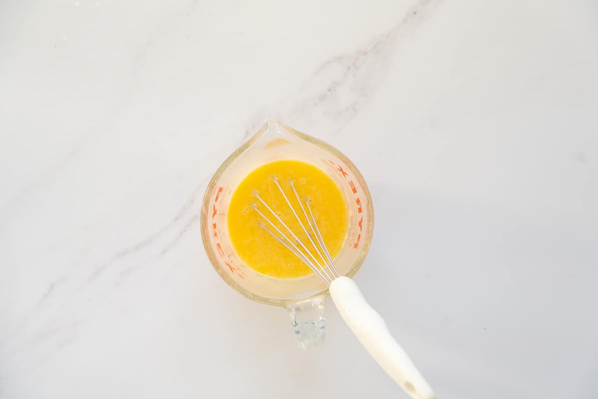 A glass mixing jug of milk, melted butter and egg mixed together.