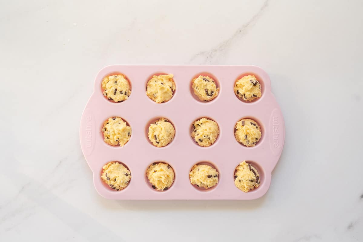 Muffin batter portion into a pink silicone mini muffin tray.