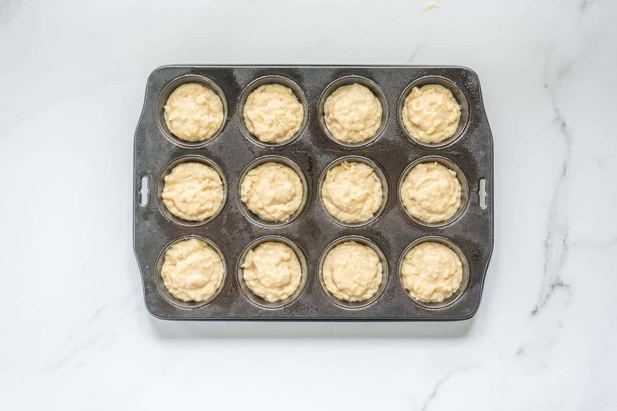 Pineapple muffin batter portioned into a 12 cup muffin tray.