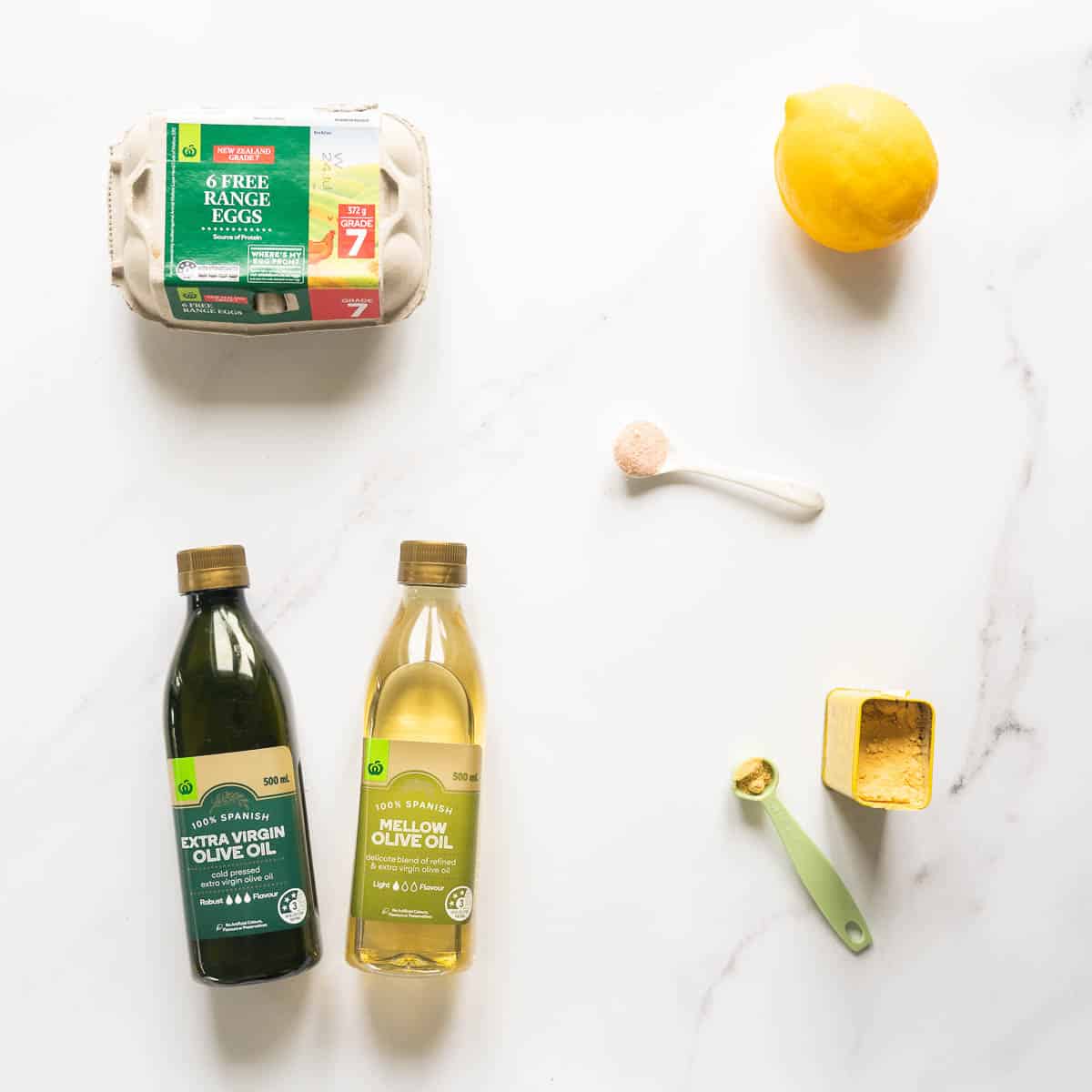 Eggs, oil, salt, mustard powder and an egg laid out on a white marble bench top.