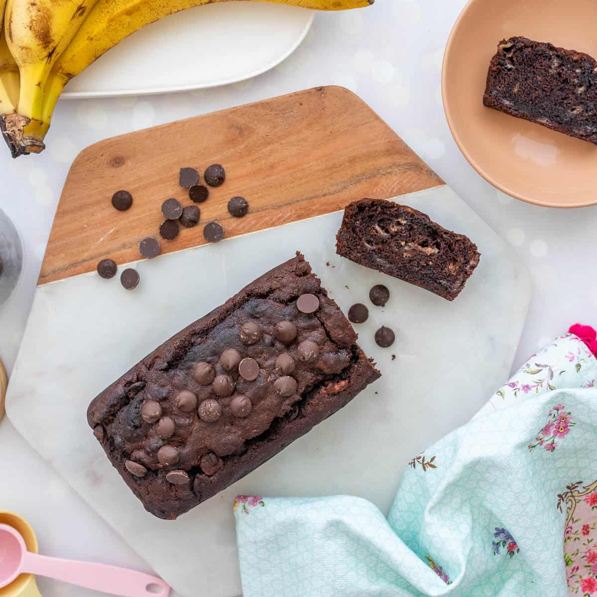 A chocolate loaf on a hexagonal marble board sprinkled with chocolate drops.