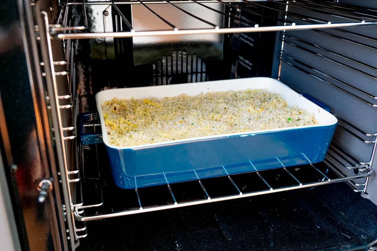 A tuna pasta bake in a blu ceramic dish sitting in an oven ready to bake.