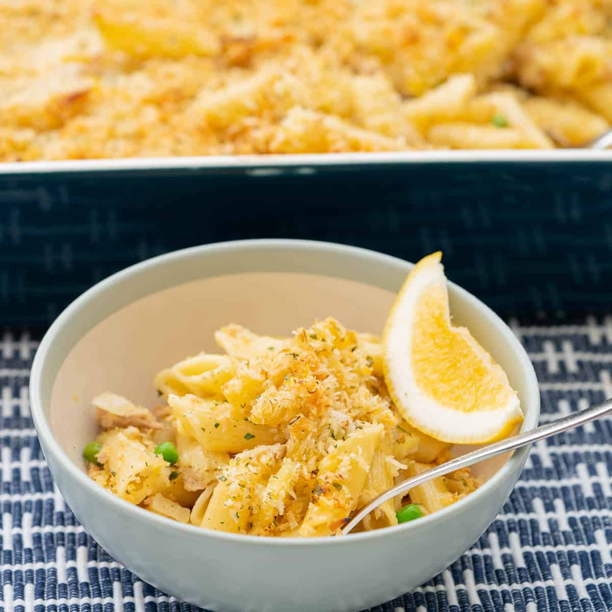 A bowl of tuna pasta bake garnished with a lemon wedge.