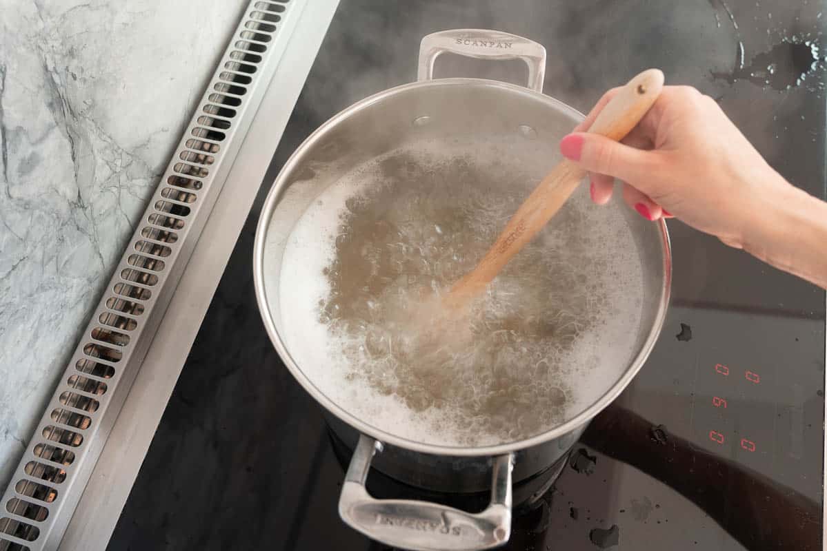 A large sauce pan of rapidly boiling pasta on a stove top.
