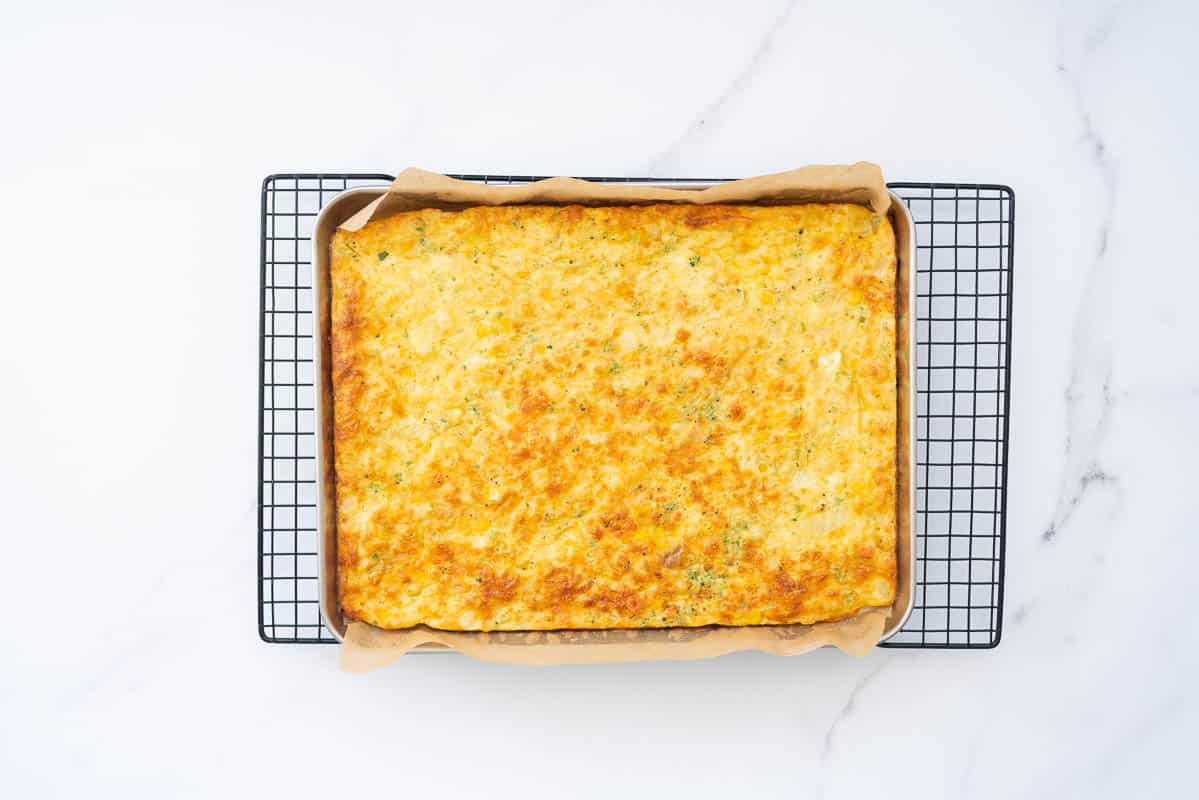 A golden baked rectangular egg dish on a cooling rack.