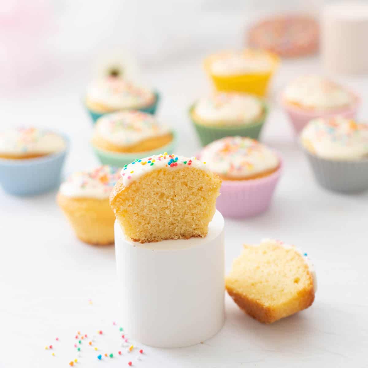 A cupcake cut in half sitting on a pedestal so that you can see the even crumb!
