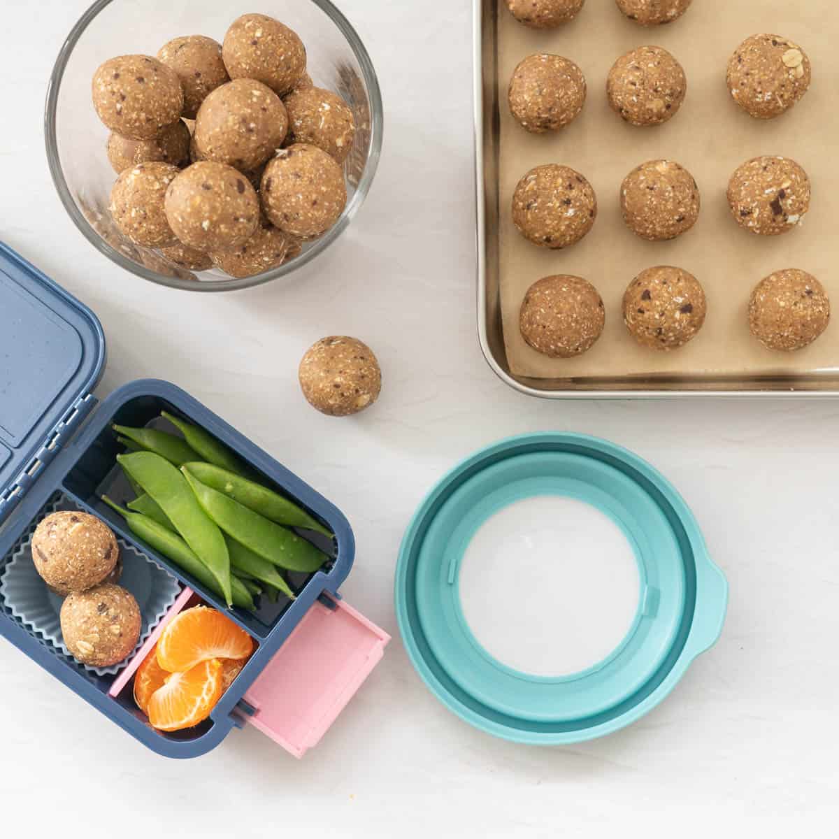 A glass jar of chilled banana bread balls, next to a small bento lunch box packed with banana bread balls.