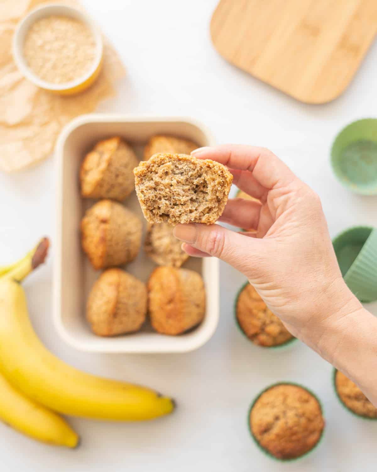 Half a muffin being held above a box of muffins.