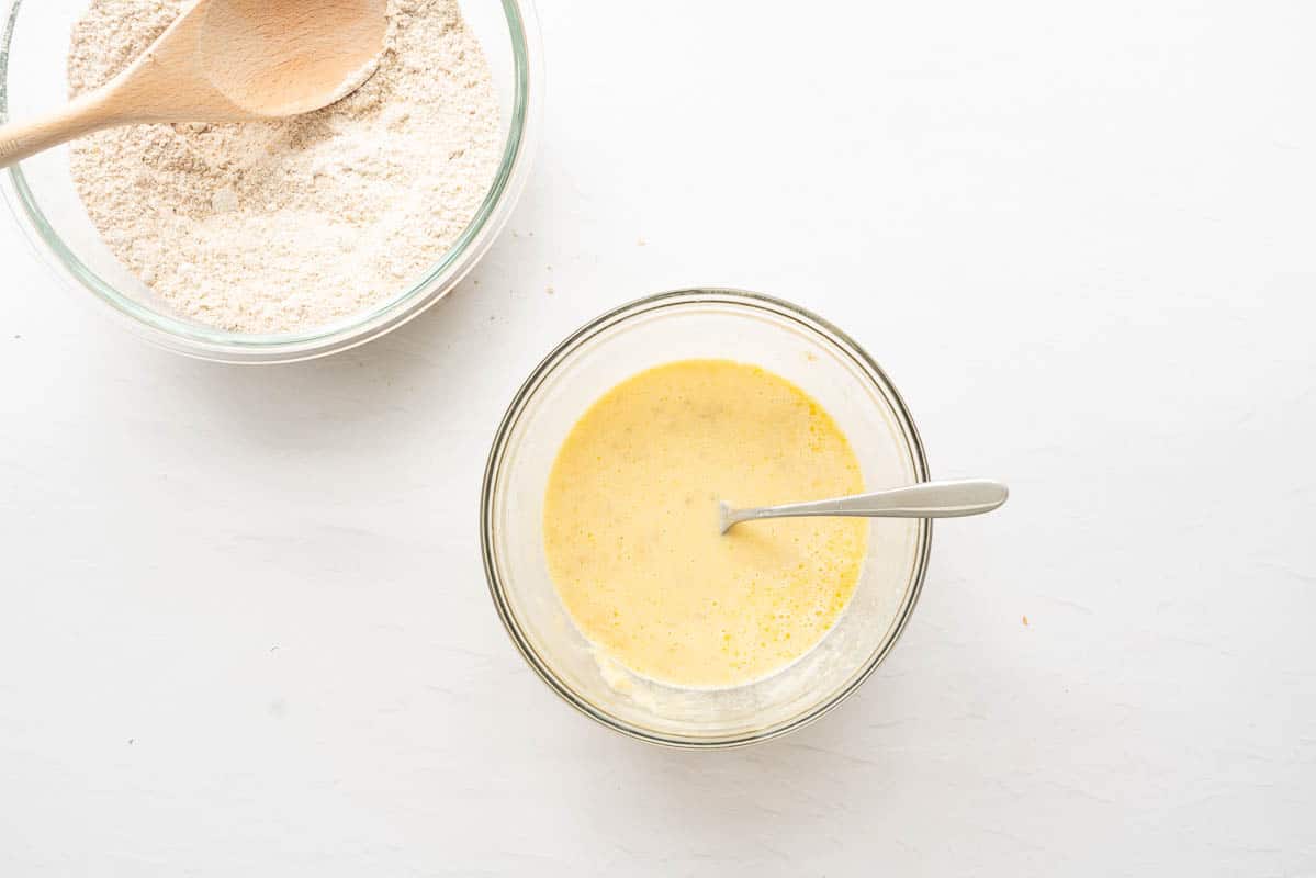 A small mixing bowl containing whisked eggs, milk and melted butter.