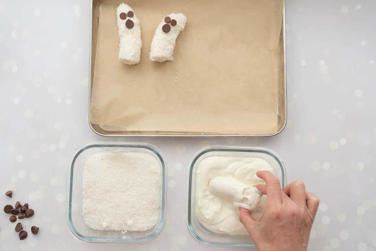 Half a banana being dipped in thick yoghurt