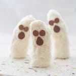 3 banana halves standing upright on a terrazzo platter decorated to look like ghosts.