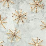Pretzels decorated to look like spider webs lying on a marble bench top.