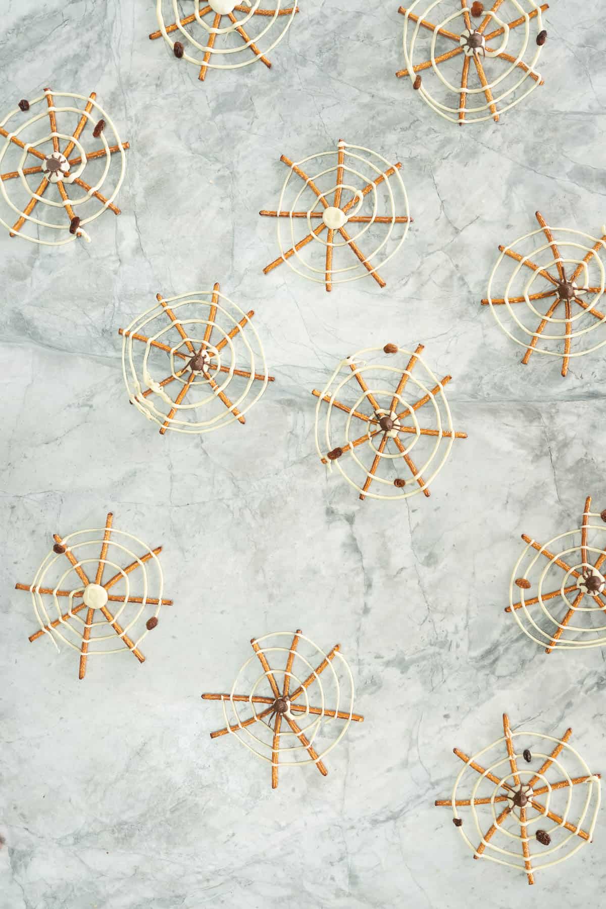Pretzles decorated to look like spider webs lying on a marble bench top.