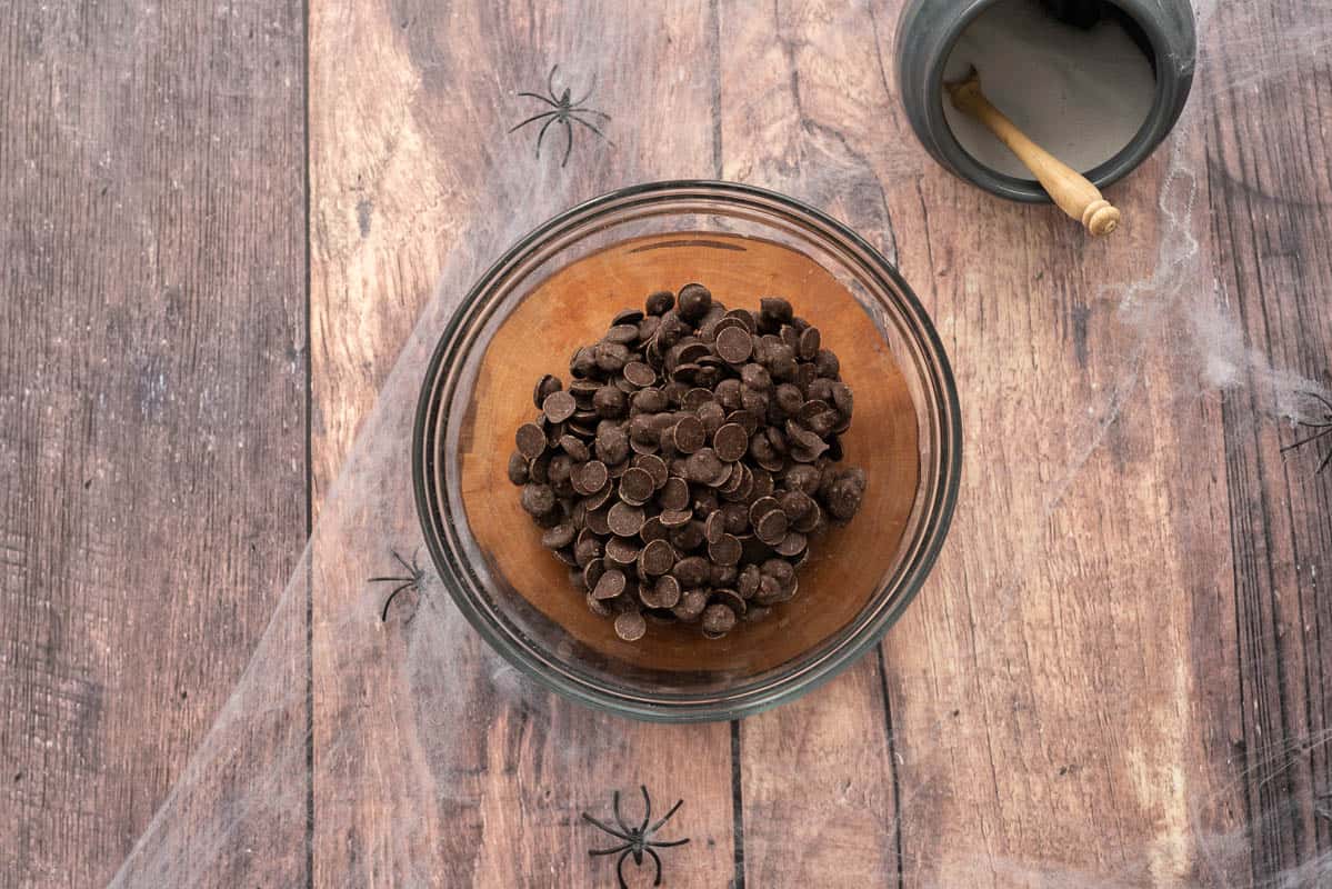 Dark chocolate drops in a medium sized glass mixing bowl.