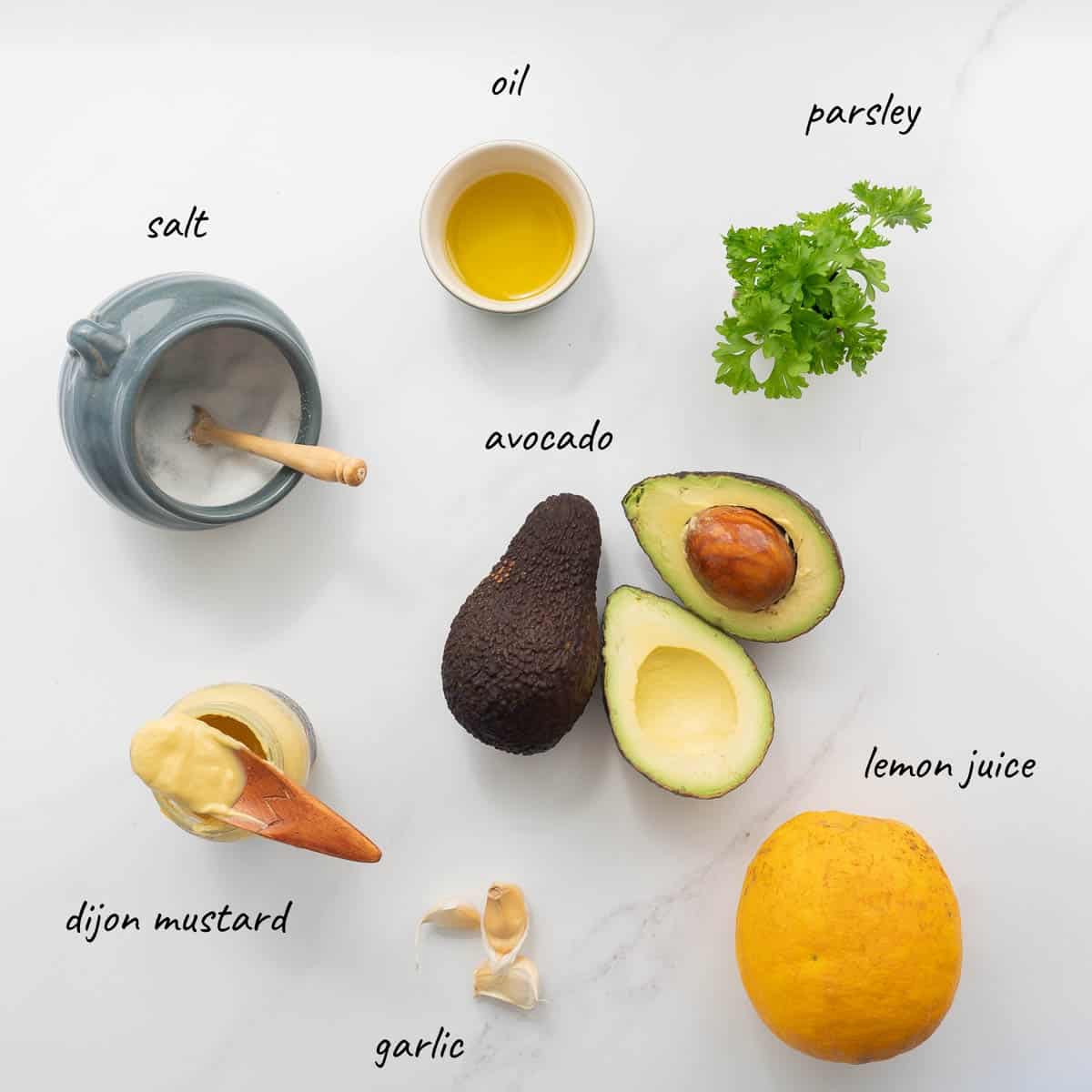 The ingredients to make avocado aioli laid out on a bench top with text overlay.