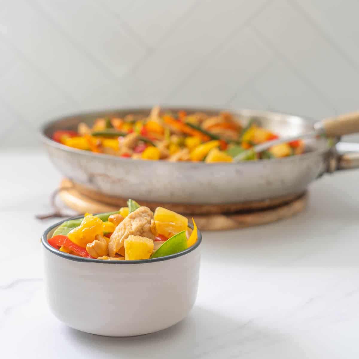 Pinepple chicken stir fry in a bowl on a white bench top.
