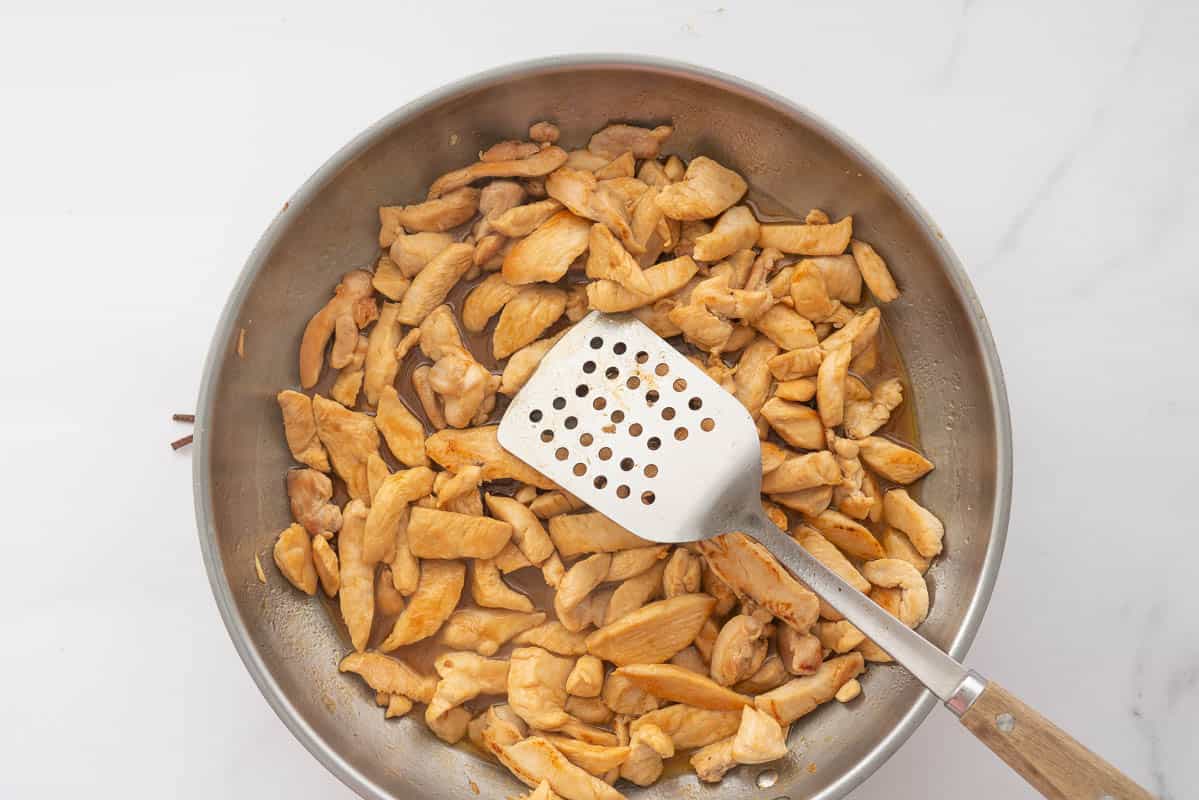 A large stainless steel fry pan of browned chicken pieces.