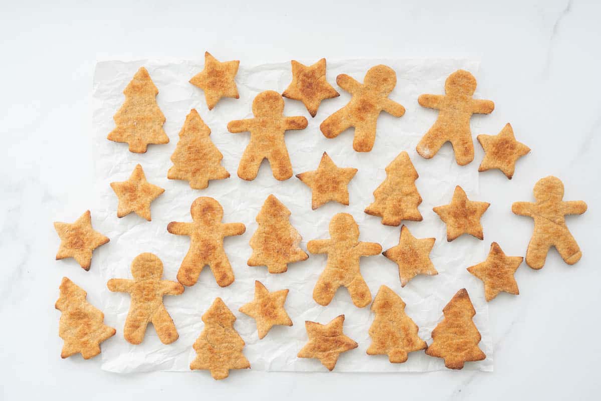 Golden baked christmas shaped cookies on a piece of crinkled parchment paper.