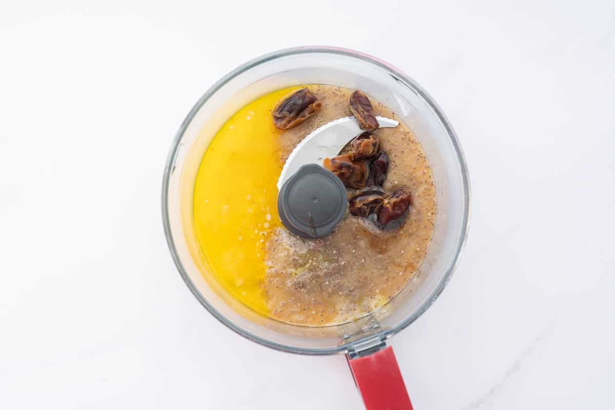 A food processor bowl with apple sauce, chia seeds dates and melted butter.