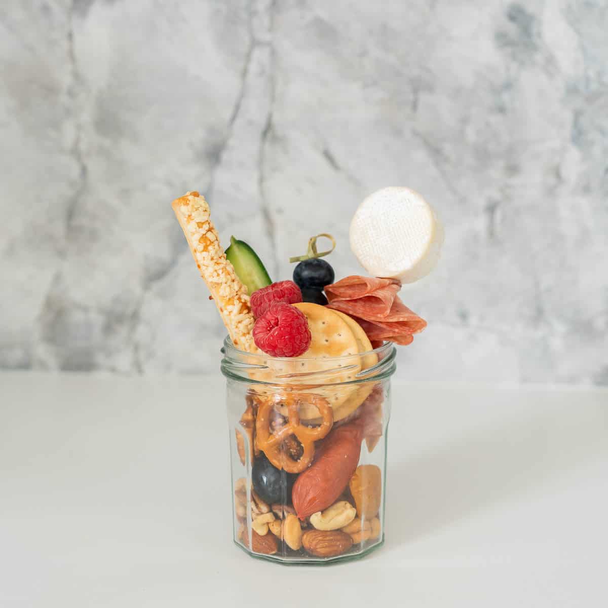 A small jar filled with charcuterie items.