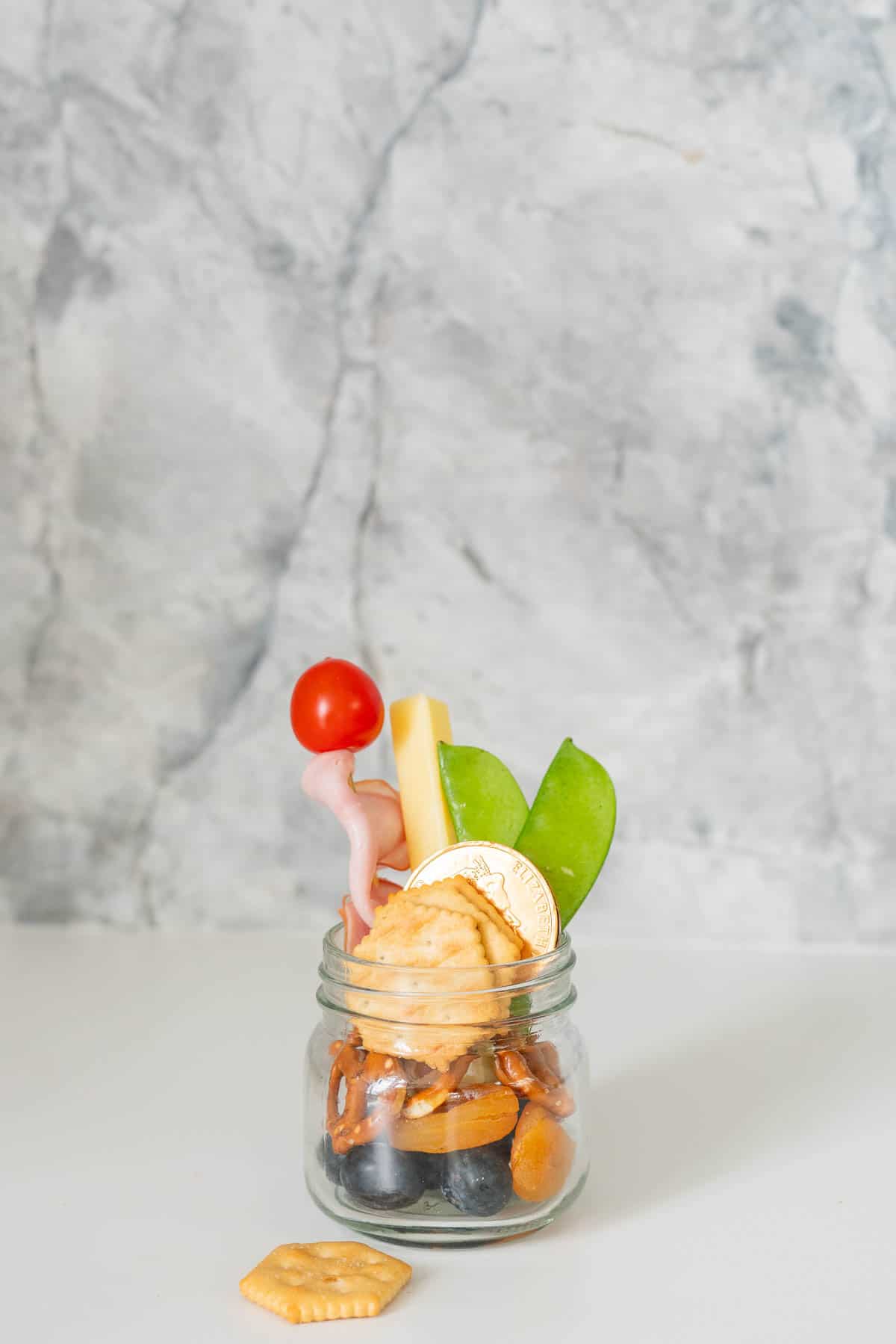 Crackers, dried fruit and ham on a skewer in a jar.