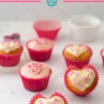 A heart shaped cupcake, decorated with pink and white on a white marble bench with text overlay