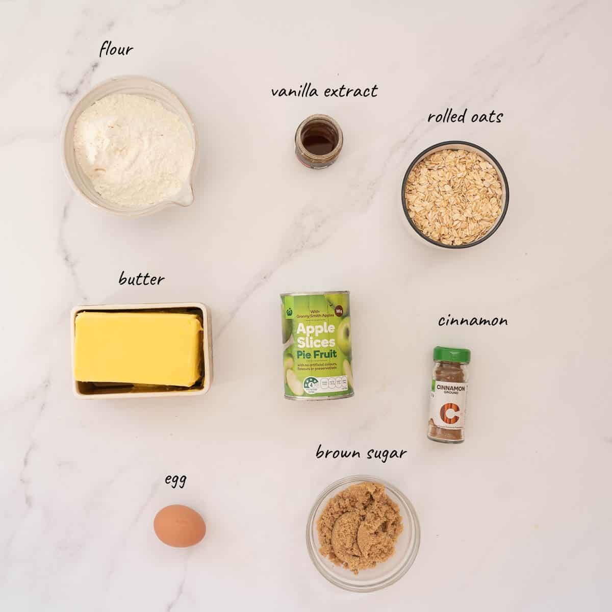 The ingredients to make apple slice laid out on a bench top with text overlay.