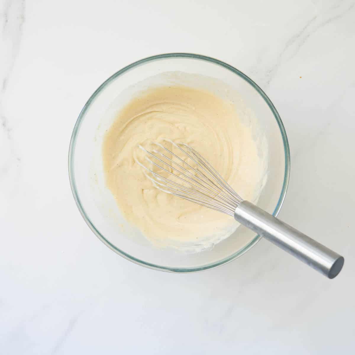 Thick pancake batter in a large glass mixing bowl.