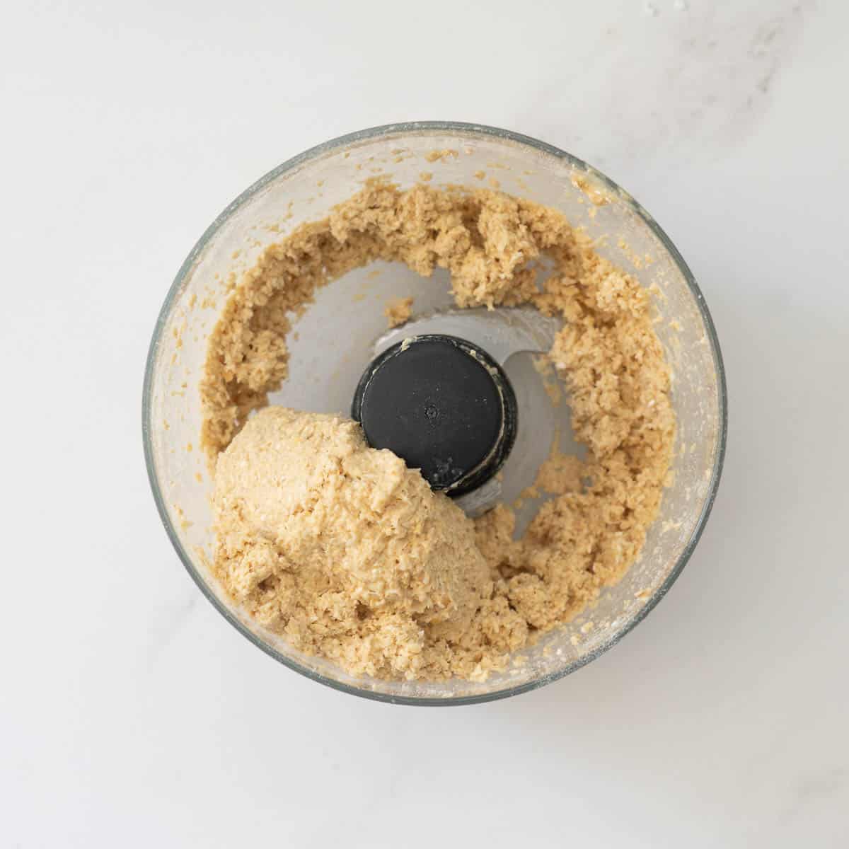 A ball of cracker dough in the bowl of a food processor.