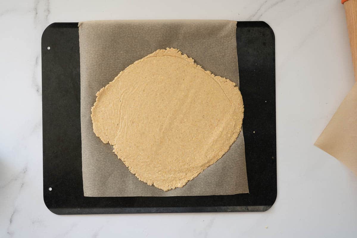 Cracker dough rolled thin on a lined baking tray.