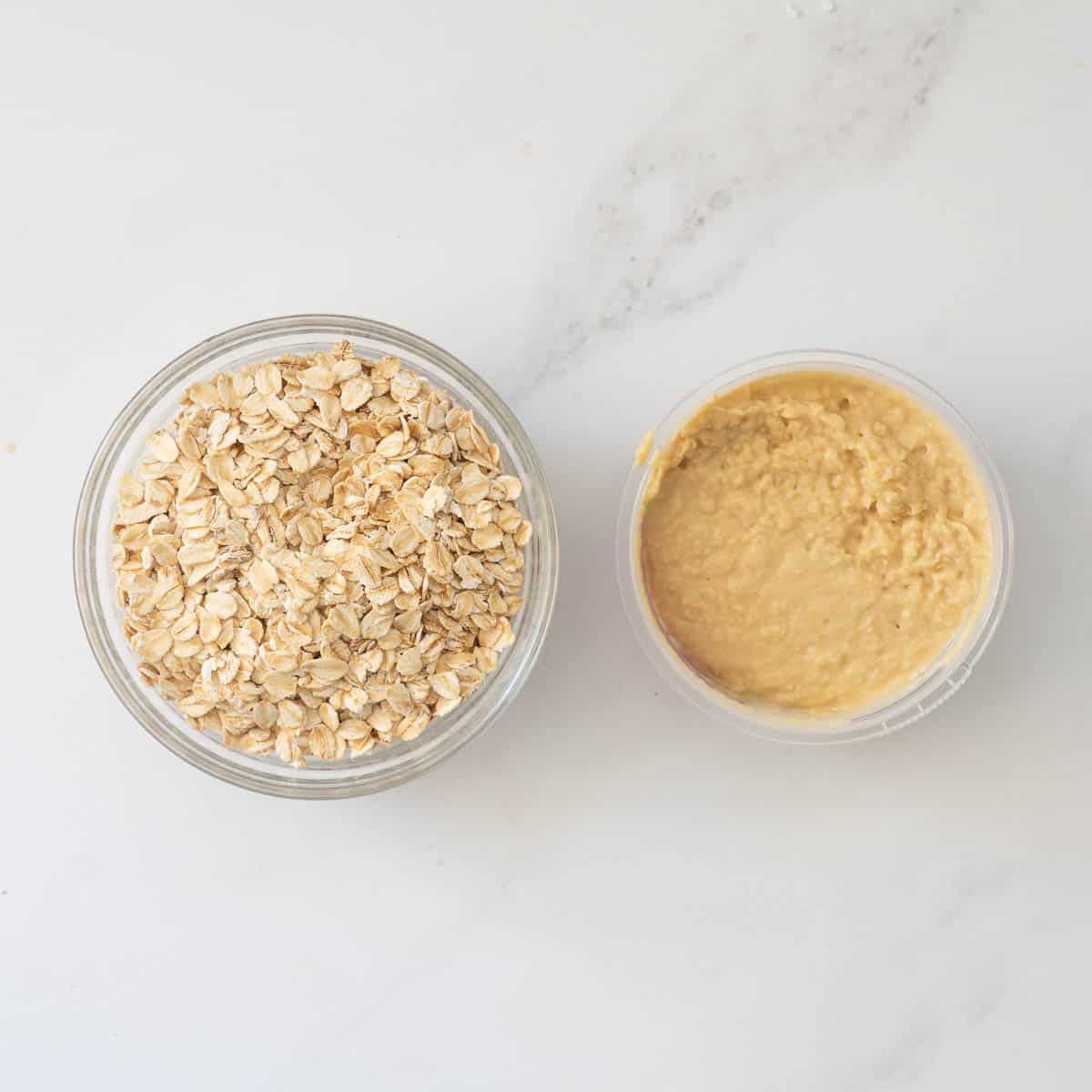 A bowl of rolled oats next to a bowl of hummus.