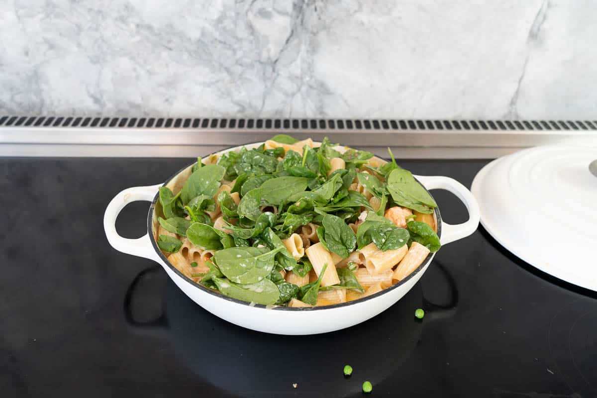 Spinach leaaves on top of cooked pasta ready to return to the oven.
