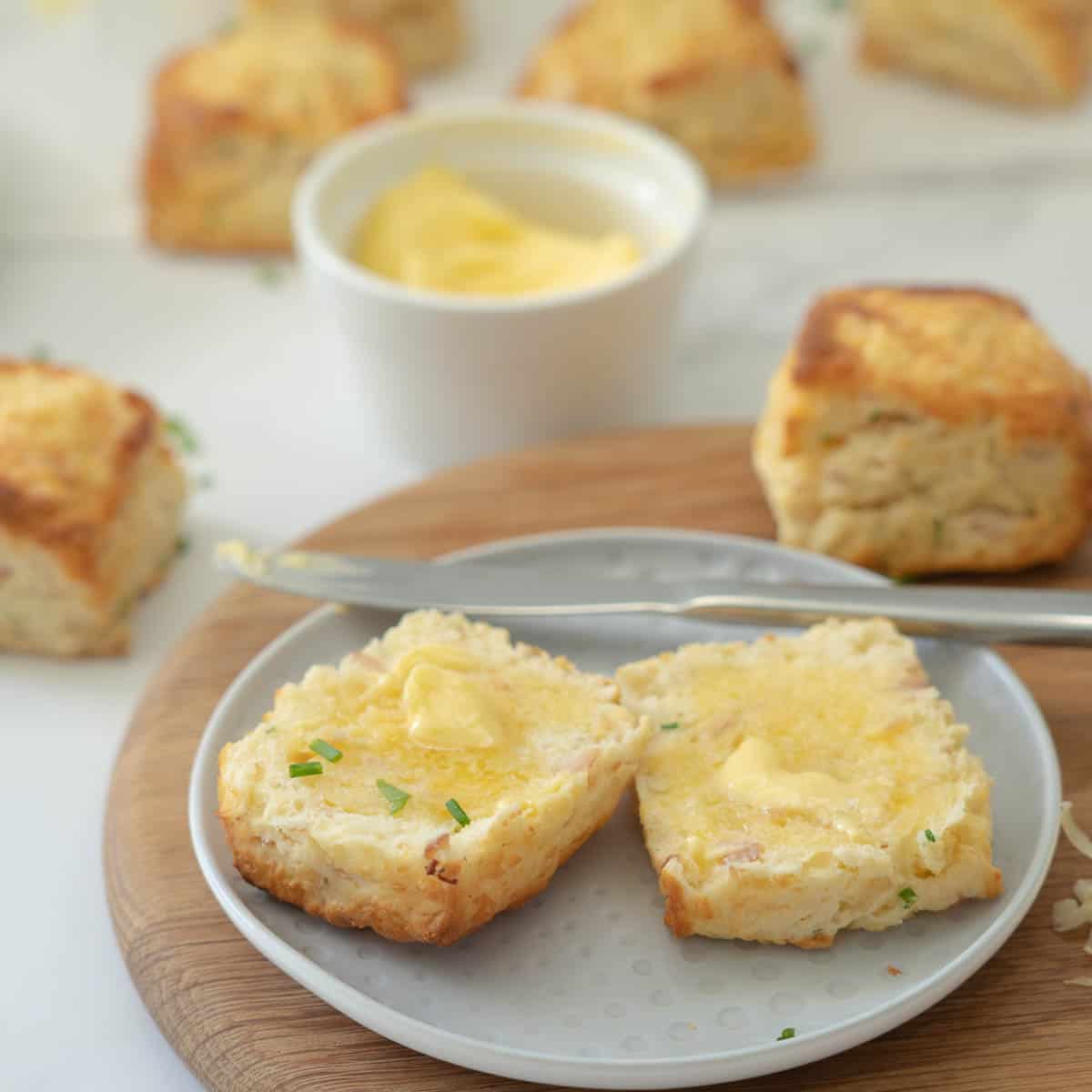 A close up of a buttered scone on a grey ceramic plate.