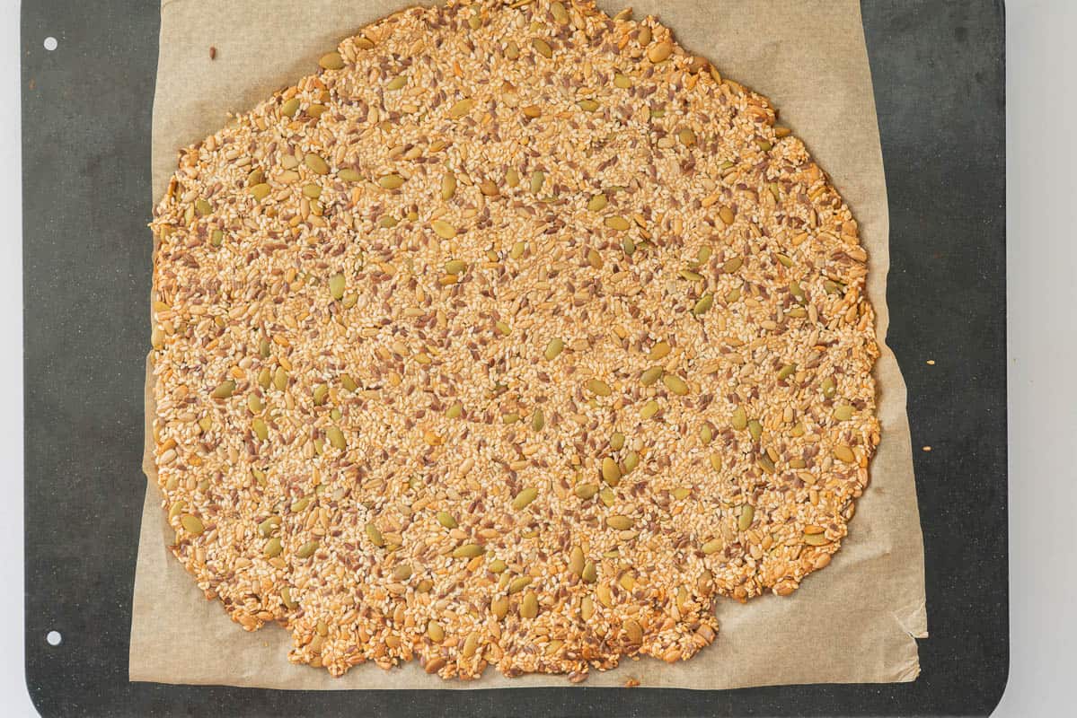 A slab of seed cracker mix, baked, golden and ready to be sliced into cracker shaped pieces.