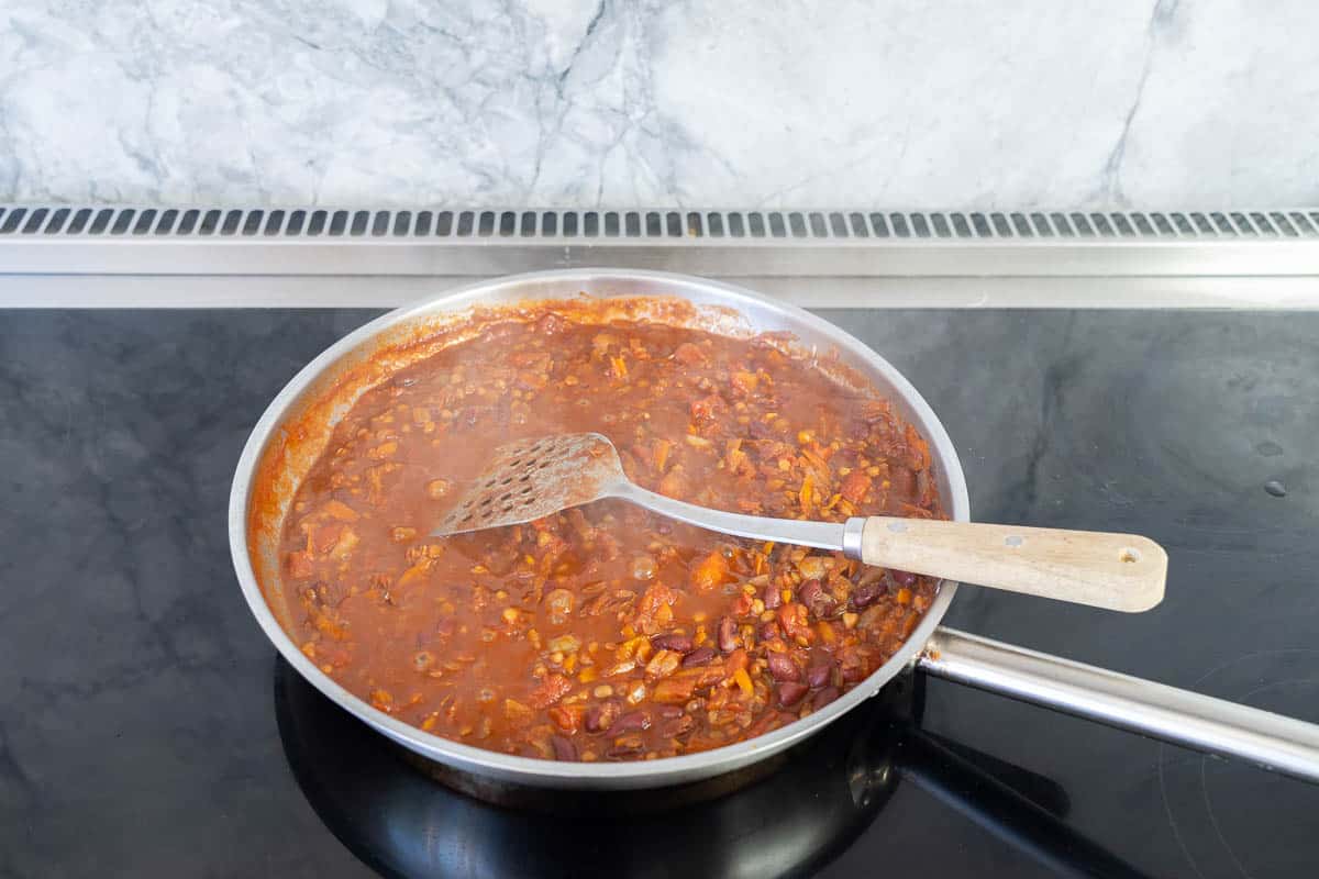 Vegetarian bean nacho mix simmering in a stainless steel fry pan.