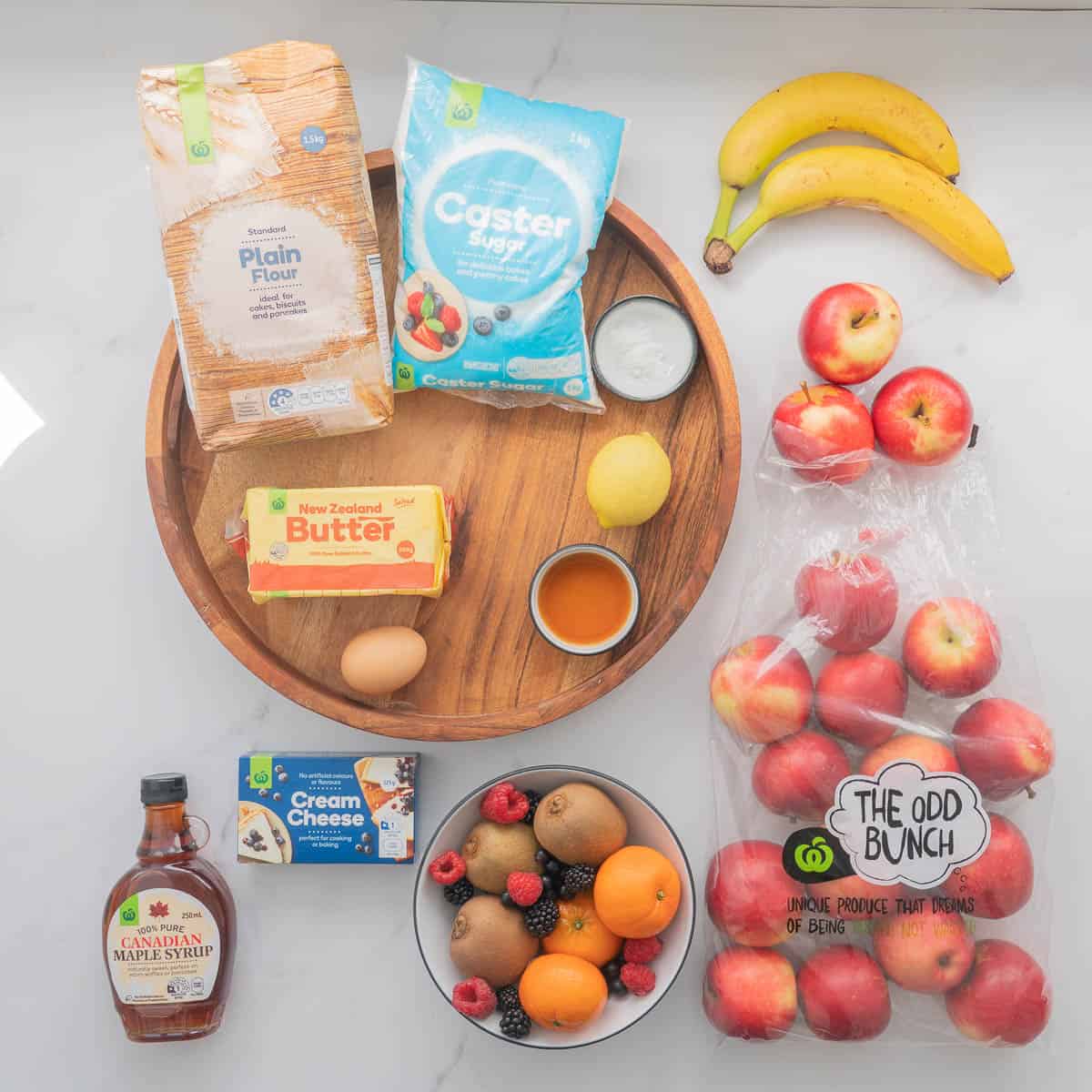 The ingredients to make an easter themed fruit pizza on a sugar cookie base laid out on a bench top.