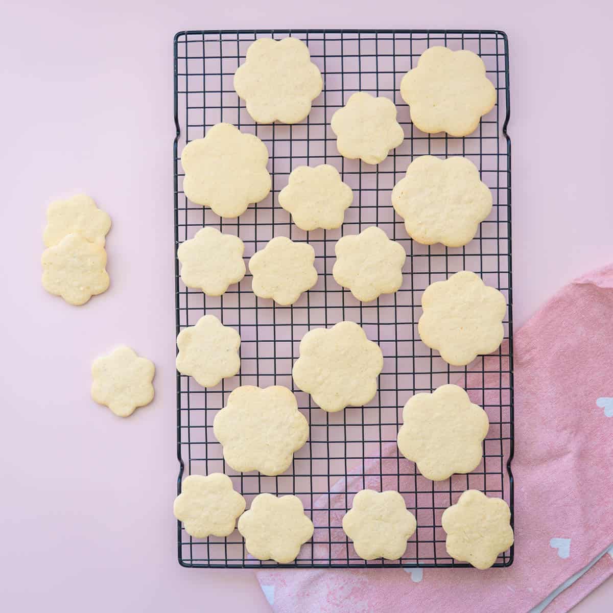 Flower shaped sugar cookies on a black wire cooling rack. 