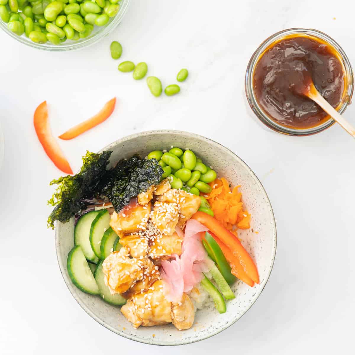 A bowl of teriyaki chicken, vegetables and rice with a bowl of teriyaki sauce next to it