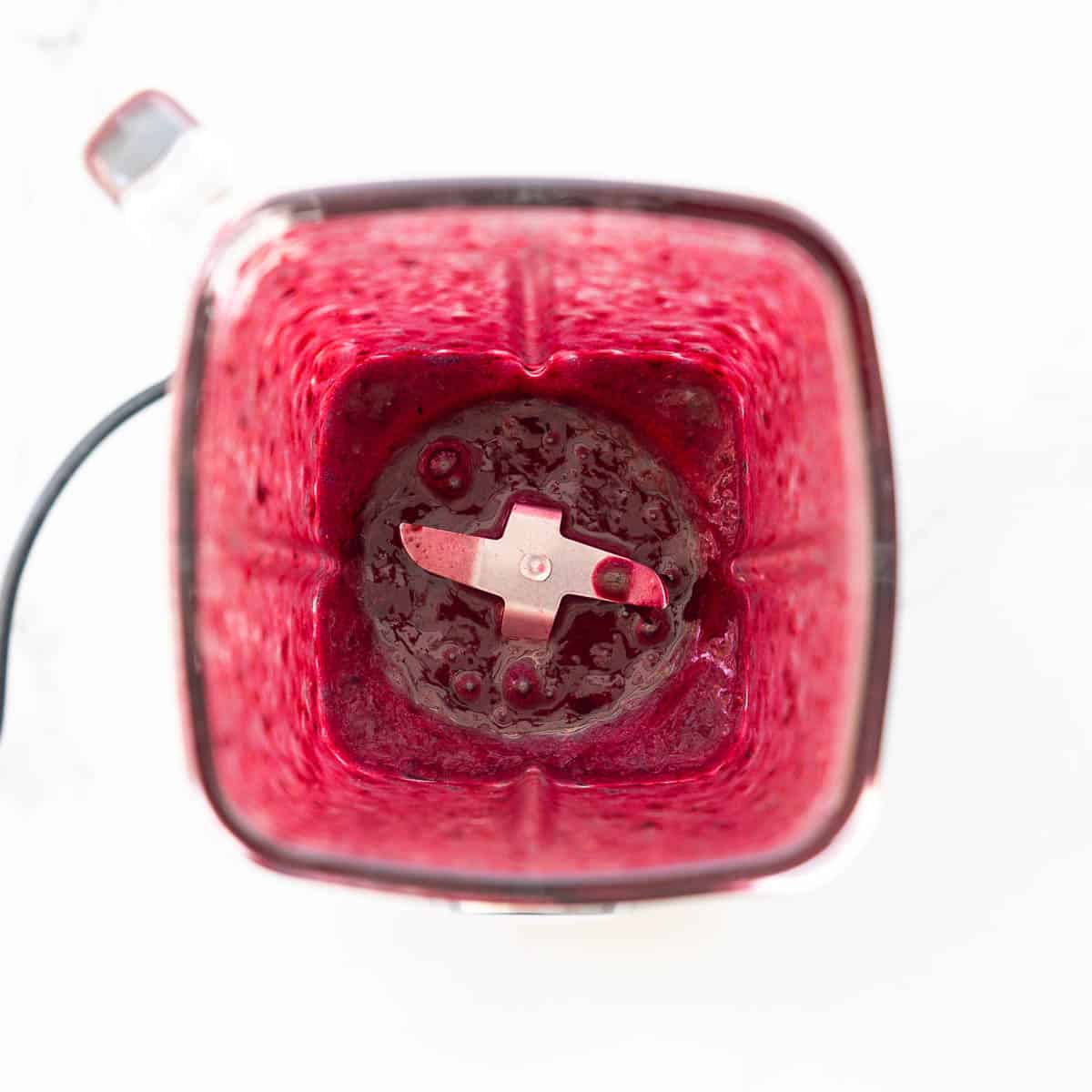 Vibrant purple fruit puree in a glass blender jug.