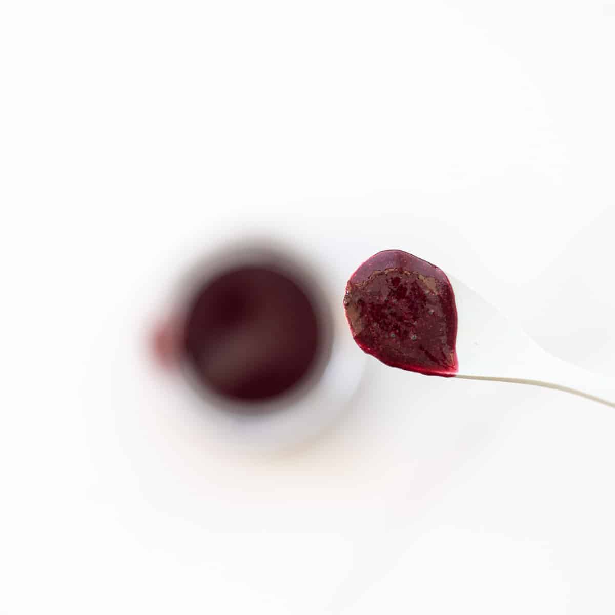 A spoonful of blueberry puree being held up to the camera.