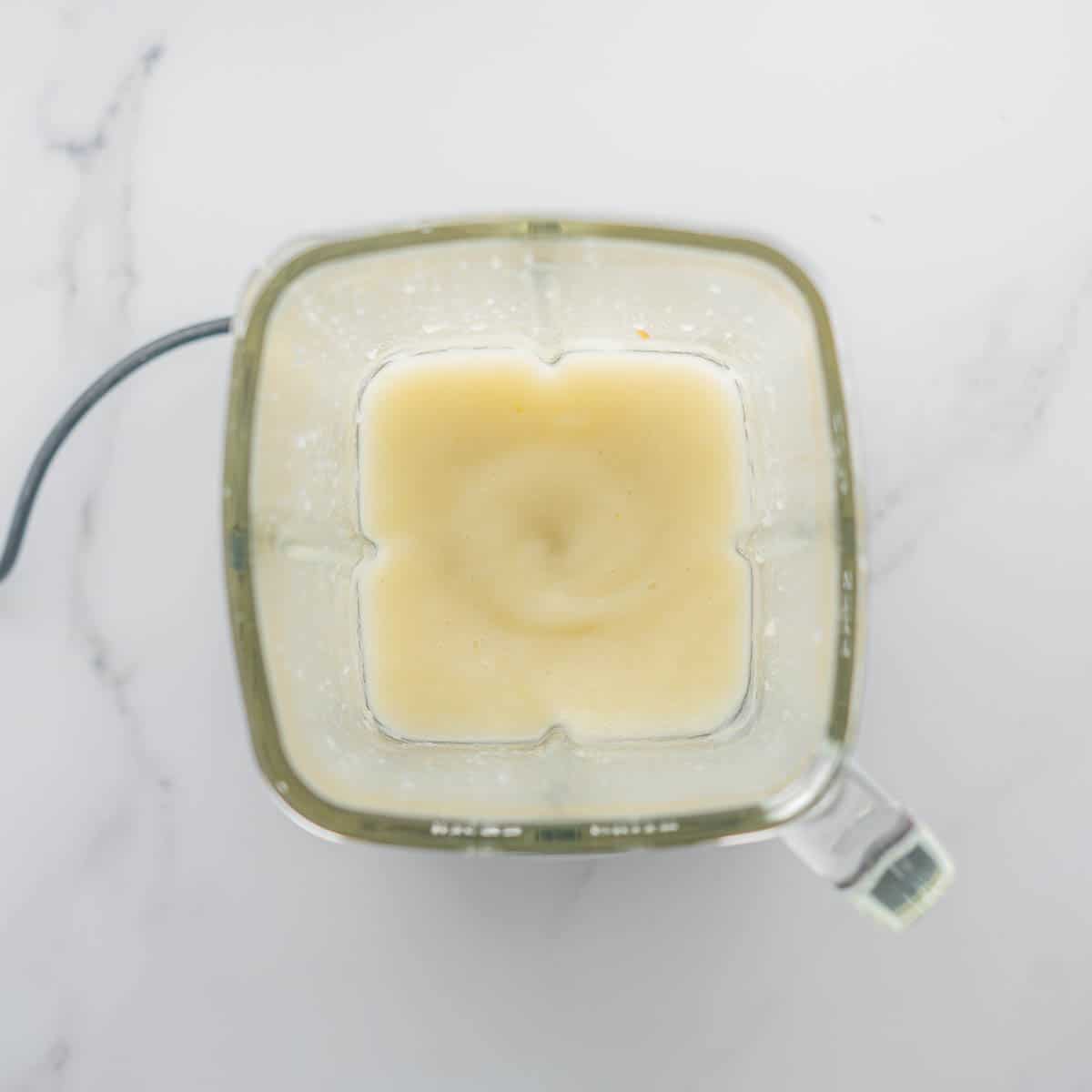 A glass blender jug of smooth pureed pears.