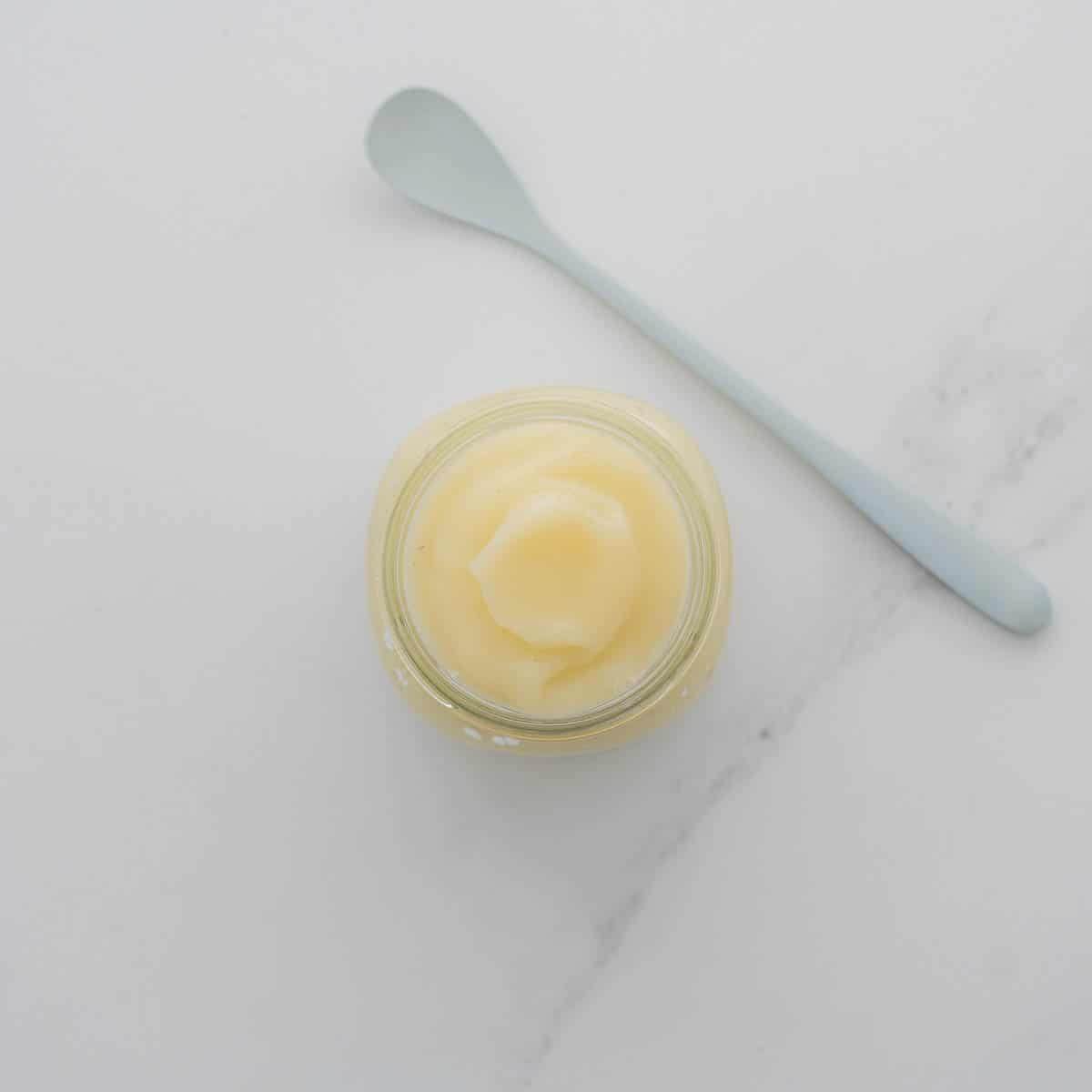 A glass jar filled with smooth fruit puree.