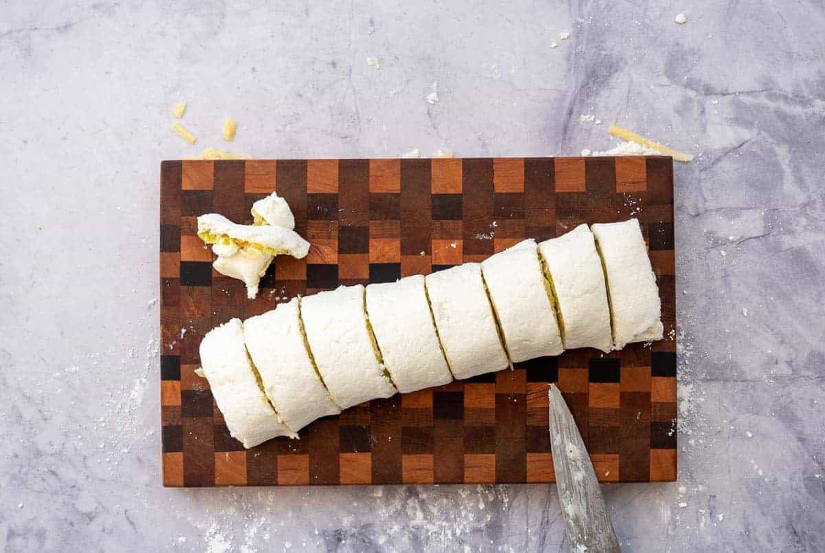 A log of pizza dough and fillings sliced into 8 scrolls.