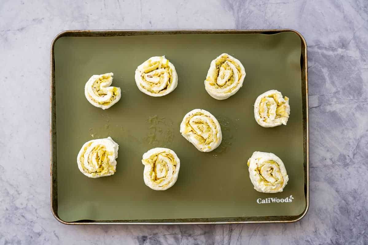 8 scrolls on a baking sheet lined with a green silicone liner.